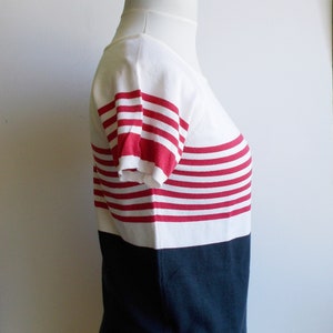 K&ouml;nnte beinhalten: Ein wei&szlig;-rot gestreiftes Kurzarm-Shirt mit einem dunkelblauen Saum.