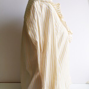 May include: A white and yellow striped long-sleeve blouse with a ruffled collar.