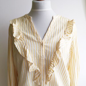 May include: A yellow and white striped long-sleeved blouse with a ruffled neckline.