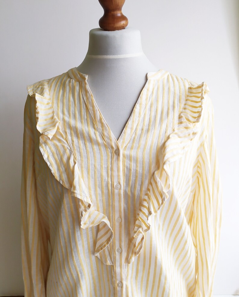 May include: A yellow and white striped long-sleeved blouse with a ruffled neckline.