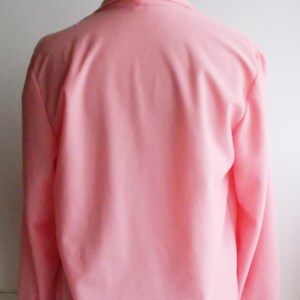 May include: A pink long-sleeved blouse with a V-neck collar. The blouse is made of a soft, lightweight fabric.