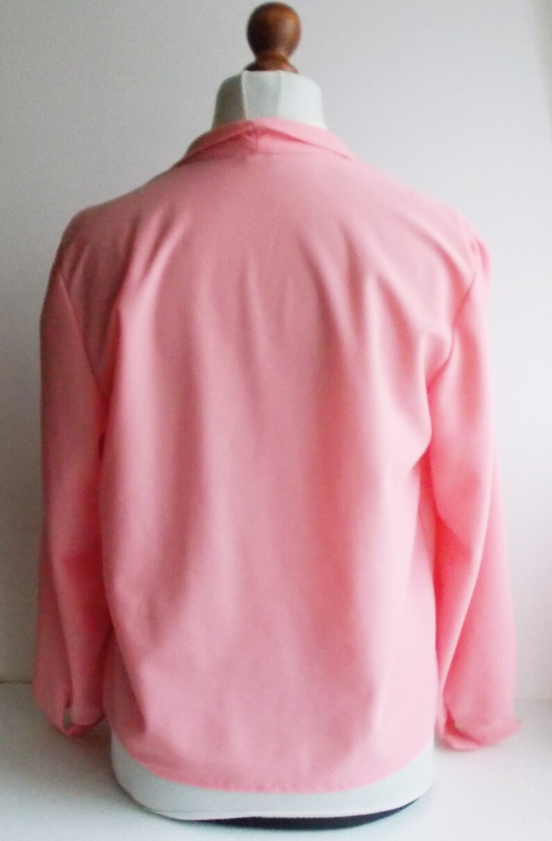 May include: A pink long-sleeved blouse with a V-neck collar. The blouse is made of a soft, lightweight fabric.