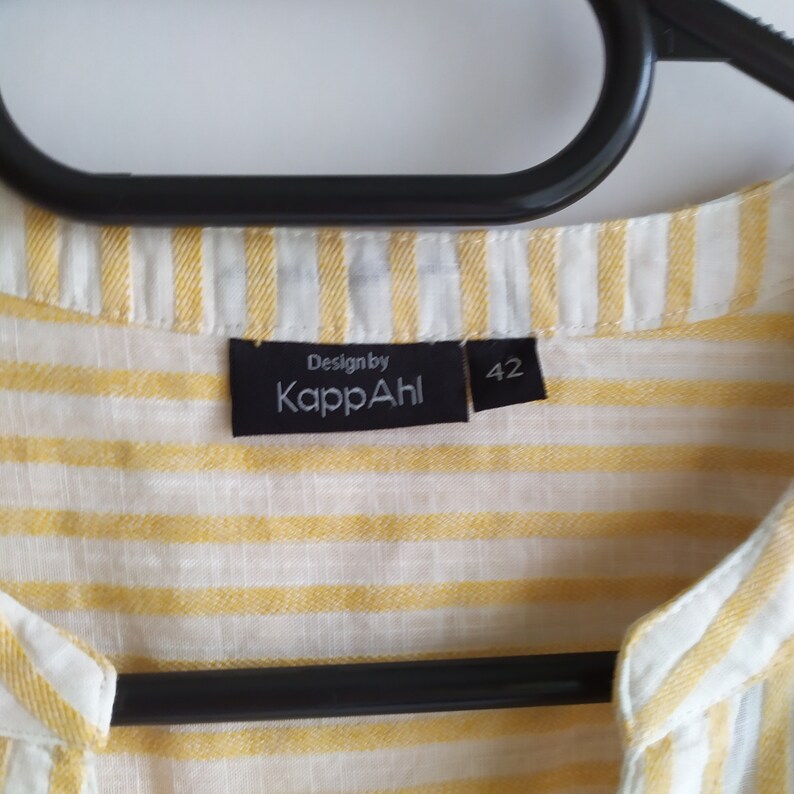May include: A yellow and white striped shirt with a black label that says "Design by KappaAhl" and "42".
