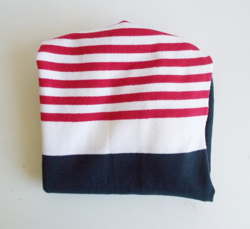 K&ouml;nnte beinhalten: Eine rot-wei&szlig; gestreifte Strickm&uuml;tze mit einem dunkelblauen Rand.