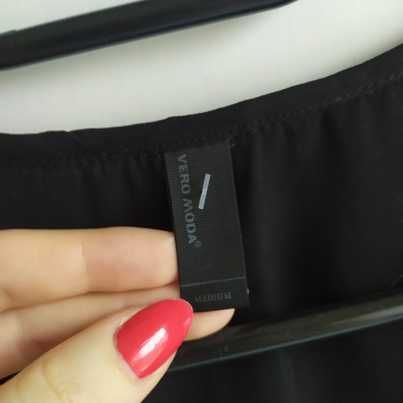 May include: Black clothing tag with the text "VERO MODA" and "MEDIUM" printed on it.