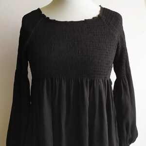 May include: Black long-sleeve blouse with a smocked bodice and a ruffled hem.