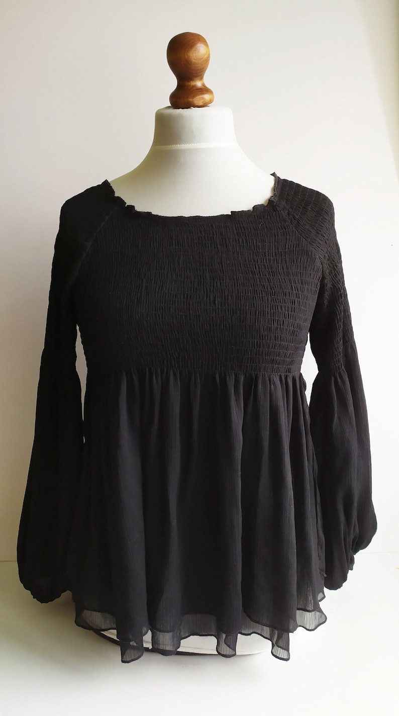 May include: Black long-sleeve blouse with a smocked bodice and a ruffled hem.