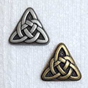 Op de afbeelding: Twee driehoekige Keltische knoopcharms, een zilveren en een gouden.