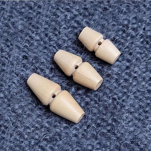 May include: Three wooden toggles in various sizes, with a hole in the centre of each piece. The toggles are light brown and have a smooth, polished finish.