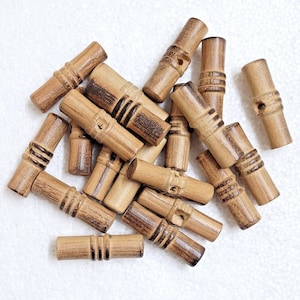 May include: A collection of 17 wooden toggle buttons in a natural brown color. The buttons have a cylindrical shape with a hole in the center and a decorative groove around the middle.