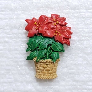 Peut inclure: Une plante de poinsettia rouge dans un panier en osier brun. La plante a des feuilles vertes et des fleurs rouges avec des centres jaunes.