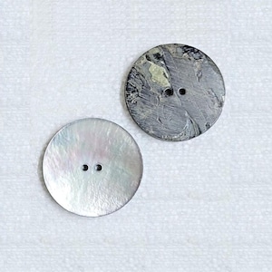 May include: Two round buttons, one is white with a pearlescent finish and two holes, the other is grey with a marbled pattern and one hole.