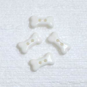 May include: Four white plastic bone-shaped buttons with two holes each.