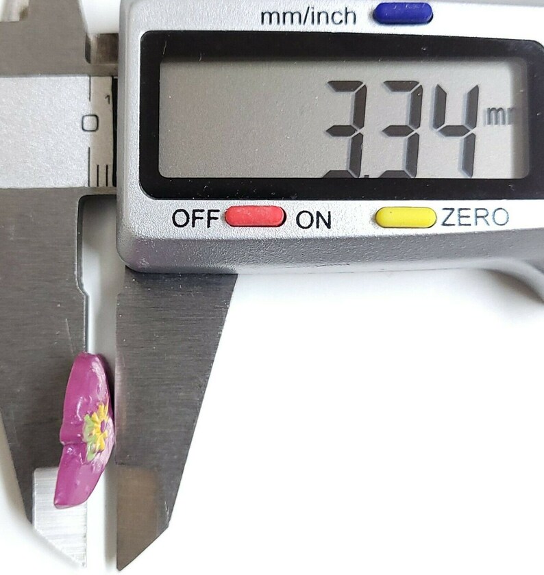 May include: A close-up of a digital caliper measuring a small pink flower with yellow accents. The caliper reads 3.74 mm.
