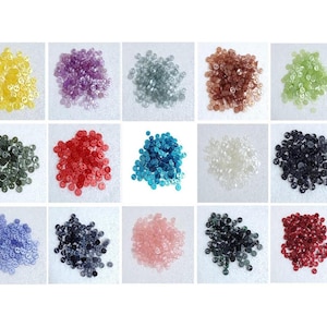 Puede incluir: Surtido de 12 colores de botones de plástico de dos agujeros. Los botones están dispuestos en una cuadrícula de 4 filas y 3 columnas. Los colores son amarillo, morado, gris, marrón, verde, negro, rojo, blanco, azul, turquesa, rosa y azul oscuro.