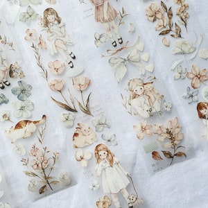 Peut inclure: Ruban adh&eacute;sif d&eacute;coratif avec des illustrations &agrave; l'aquarelle de filles, de fleurs et d'animaux aux couleurs pastel douces. Le ruban comprend des images de filles en robes, de chats, de lapins et d'&eacute;l&eacute;ments floraux. Le th&egrave;me g&eacute;n&eacute;ral est fantaisiste et vintage.