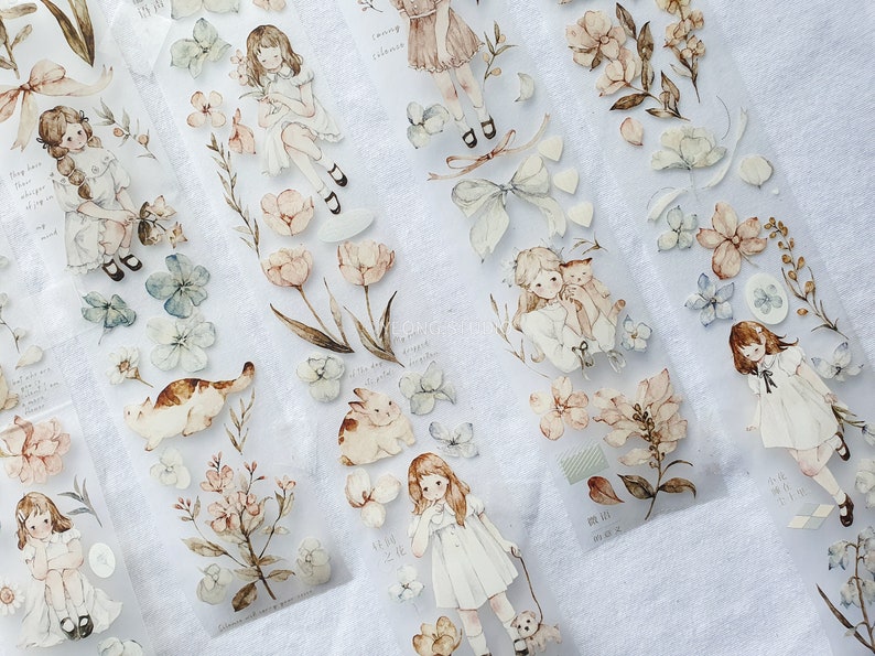 Peut inclure: Ruban adh&eacute;sif d&eacute;coratif avec des illustrations &agrave; l'aquarelle de filles, de fleurs et d'animaux aux couleurs pastel douces. Le ruban comprend des images de filles en robes, de chats, de lapins et d'&eacute;l&eacute;ments floraux. Le th&egrave;me g&eacute;n&eacute;ral est fantaisiste et vintage.