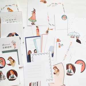 May include: A set of decorative cards with illustrations of people and floral designs. The cards are white with a variety of borders and patterns. Some cards have text in a foreign language.