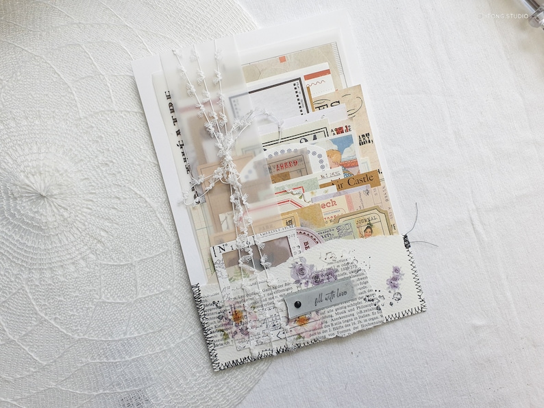 K&ouml;nnte beinhalten: Ein wei&szlig;er Umschlag mit einem gen&auml;hten Rand, gef&uuml;llt mit Vintage-Ephemera, darunter Papierschnipsel, Briefmarken und ein kleines Etikett mit der Aufschrift "Mit Liebe f&uuml;llen".