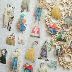 Könnte beinhalten: Aquarell-Aufkleber mit Modeillustrationen von Frauen in verschiedenen Posen und Outfits. Die Aufkleber zeigen Frauen in Jeans, Röcken und Kleidern, mit Accessoires wie Sonnenbrillen, Hüten und Taschen. Ein Schmetterlingsaufkleber ist ebenfalls enthalten.