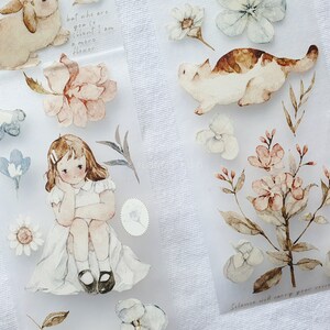 Peut inclure: Autocollants aquarelle avec un lapin, un chat, une fille et des &eacute;l&eacute;ments floraux aux couleurs pastel. Les autocollants incluent du texte manuscrit. Th&egrave;me g&eacute;n&eacute;ral : d&eacute;licat et fantaisiste.