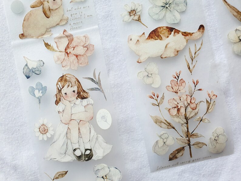 Peut inclure: Autocollants aquarelle avec un lapin, un chat, une fille et des &eacute;l&eacute;ments floraux aux couleurs pastel. Les autocollants incluent du texte manuscrit. Th&egrave;me g&eacute;n&eacute;ral : d&eacute;licat et fantaisiste.