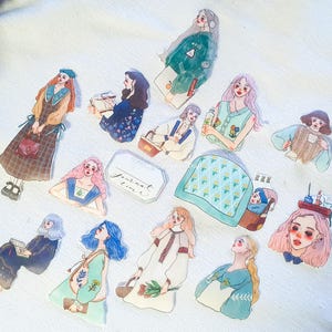 May include: A set of 12 colorful stickers featuring illustrations of girls with different hairstyles and outfits. The stickers are perfect for adding a touch of whimsy to journals, planners, and other craft projects.