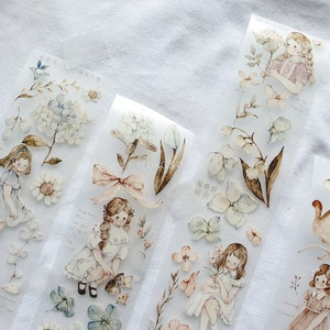 Peut inclure: Ruban adh&eacute;sif d&eacute;coratif avec des illustrations &agrave; l'aquarelle de filles, de fleurs et d'animaux. Le ruban comprend des images de marguerites, d'hortensias et de lapins. Les illustrations sont dans des couleurs pastel douces.