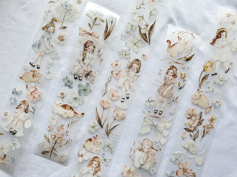 Peut inclure: Ruban adh&eacute;sif washi d&eacute;coratif avec des illustrations &agrave; l'aquarelle de filles, de fleurs et d'animaux comme des lapins et des chats. Le ruban a un fond transparent avec une esth&eacute;tique vintage d&eacute;licate.