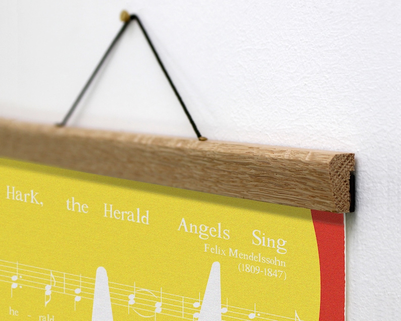 May include: A poster with the text "Hark, the Herald Angels Sing" and musical notes, displayed with a wooden hanger. The poster has a yellow background with white text and musical notes, and a red border.