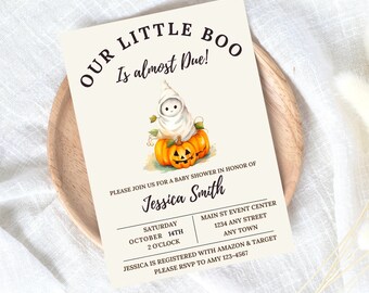 May include: A white and cream baby shower invitation featuring a cartoon ghost holding a pumpkin. The text reads "Our Little Boo Is almost Due!" and includes the date, time, and location of the event. The invitation also includes the name "Jessica Smith" and the text "Jessica is registered with Amazon & Target. Please RSVP to Amy 123-4567."
