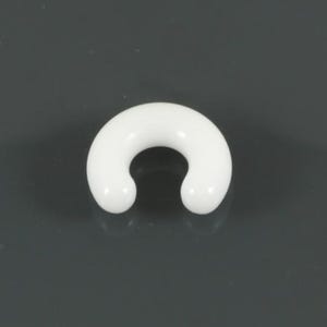 May include: A smooth, solid white circular horseshoe-shaped body jewellery piece with rounded ends. The object features a continuous, glossy finish and a curved, open design that forms a semi-circle, presenting a clean and simple aesthetic.