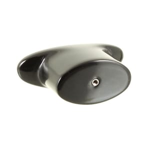 May include: A smooth, glossy black cabinet knob with an elongated, oval-shaped front face. The centre of the oval features a small, circular metal-lined hole for mounting. The knob has a curved, ergonomic profile that tapers towards the back.
