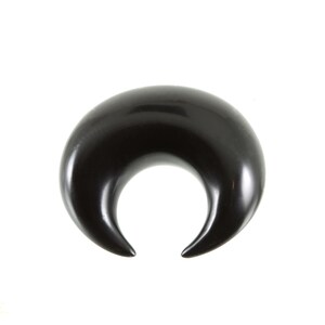 May include: A black crescent moon shaped ear gauge made of wood.