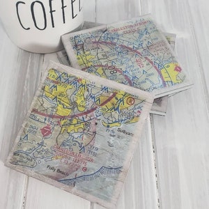 May include: Set of four coasters featuring vintage maps of Charleston, South Carolina. The coasters are made of wood and have a distressed finish. Each coaster features a different section of the map, including the Charleston Executive Airport, Folly Beach, and the Sullivan's Island area.