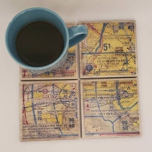 May include: Set of four coasters featuring vintage maps of Phoenix, Arizona. Each coaster is made of wood and has a yellow, red, and blue color scheme. The coasters feature various landmarks and roads, including the Phoenix Sky Harbor International Airport, Glendale, and the Metro Center.