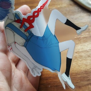 May include: A clear sticker featuring an anime character with blue hair, wearing a white shirt with a blue skirt and red accents. The character is depicted with a red string attached to their chest.