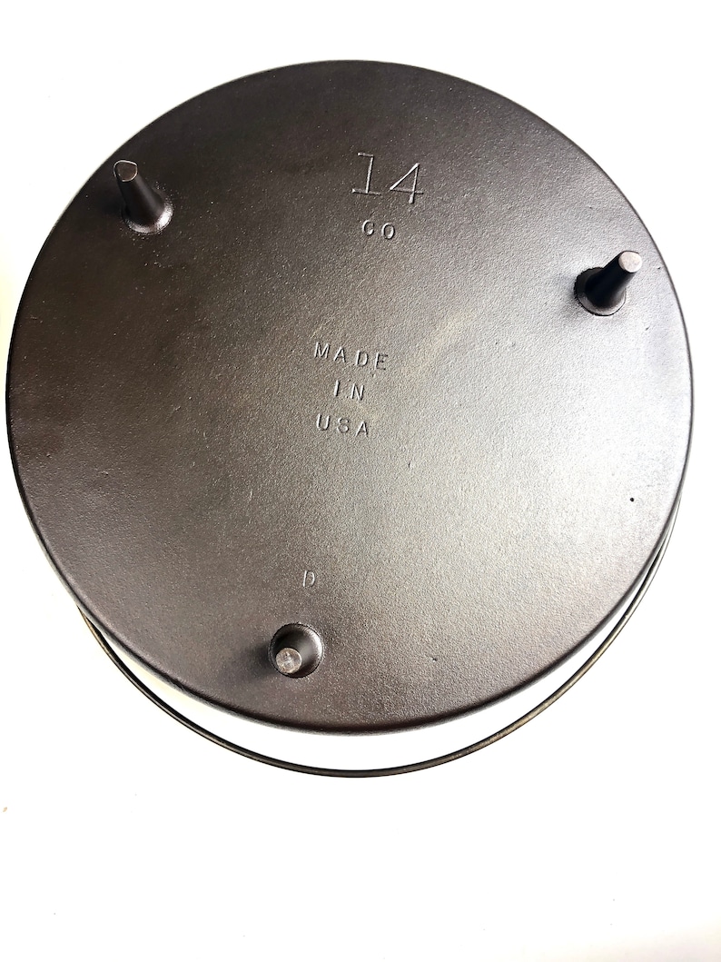 Puede incluir: La parte inferior de una olla de hierro fundido con tres patas. La olla est&aacute; marcada con "14 CO" y "MADE IN USA".