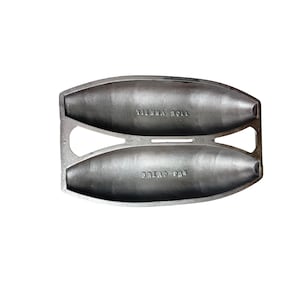 May include: A silver-colored metal baking mold featuring two elongated, oval-shaped cavities for baking bread. The top cavity is embossed with the text VIENNA ROLL, and the bottom cavity is embossed with the text BREAD PAN. The mold has a flat frame.