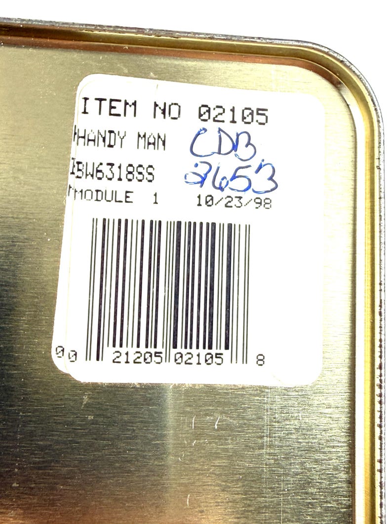 May include: A close-up of a metallic container with a white label. The label includes the text "ITEM NO 02105 HANDY MAN" and a barcode. Handwritten blue numbers and the date "10/23/98" are also visible.