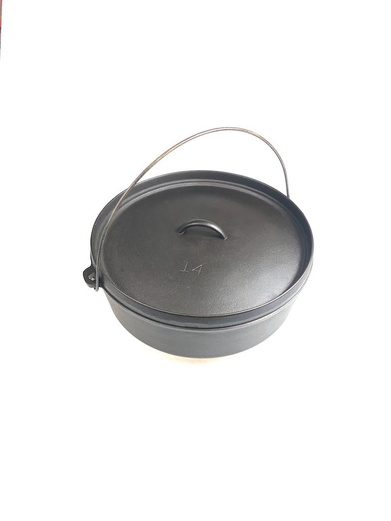 Puede incluir: Cazuela de hierro fundido negro con tapa y asa de alambre. La tapa tiene una peque&ntilde;a asa y el n&uacute;mero "14" est&aacute; grabado en la tapa.