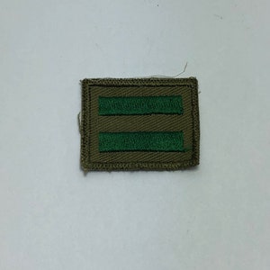 May include: A green and brown rectangular patch with two horizontal green stripes.