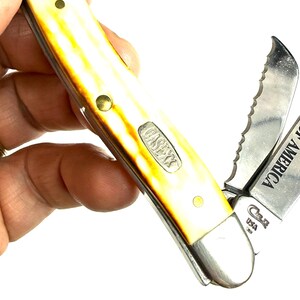 May include: A Case XX pocket knife with a yellow and brown handle. The knife has multiple blades, including a serrated one, and the text "CHARTER MEMBER" is visible on one blade. The knife is marked "Case XX USA".