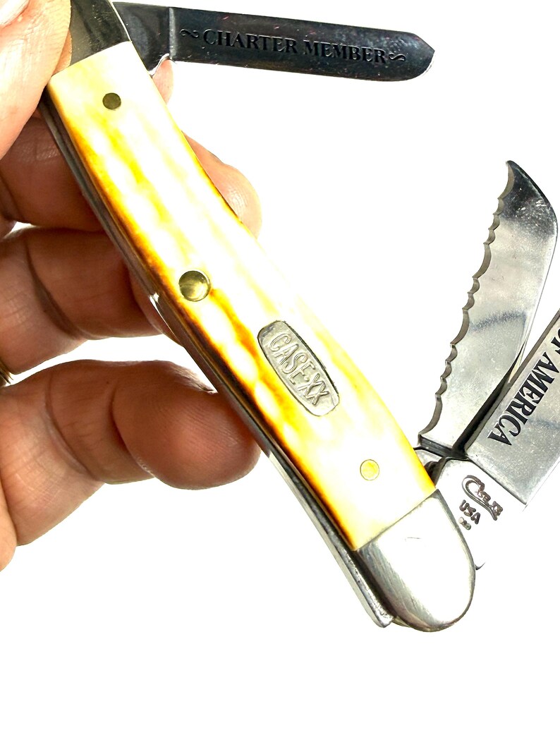 May include: A Case XX pocket knife with a yellow and brown handle. The knife has multiple blades, including a serrated one, and the text "CHARTER MEMBER" is visible on one blade. The knife is marked "Case XX USA".