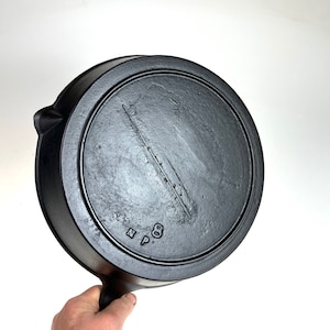 May include: Black cast iron skillet with a handle. The bottom of the skillet is marked with "N.P. 8".