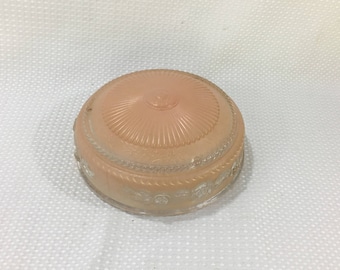 May include: A vintage, pale pink glass ceiling light fixture with a decorative, embossed design. The fixture has a round, dome-shaped top and a scalloped edge.