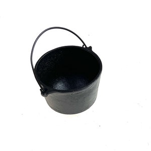 May include: A black cast iron pot with a handle. The pot is empty and has a smooth, shiny surface.