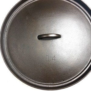 Puede incluir: Tapa de olla de hierro fundido negro con asa y el n&uacute;mero "14" inscrito en la parte superior.