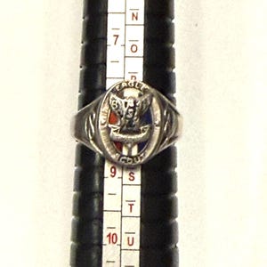 May include: Silver-toned ring with an oval emblem featuring an eagle and the text "EAGLE SCOUT". The emblem has red, white, and blue accents. The ring is on a black ring sizer.