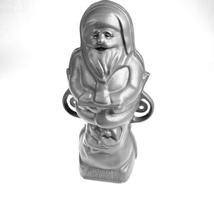 May include: A silver-colored metal mold shaped like Santa Claus holding a bag of gifts. The mold has the text "Hello Kiddies!" on the base.